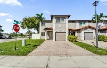 Multi-level exterior featuring a stucco facade, tile roofing, paver driveway, attached garage, and landscaping
