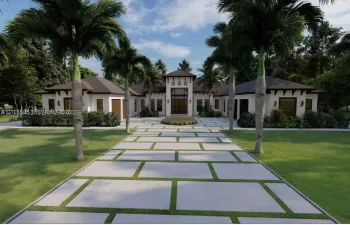 Contemporary exterior featuring a stucco facade, multi-gabled roofline, paver driveway with integrated turf grid, and mature palm trees