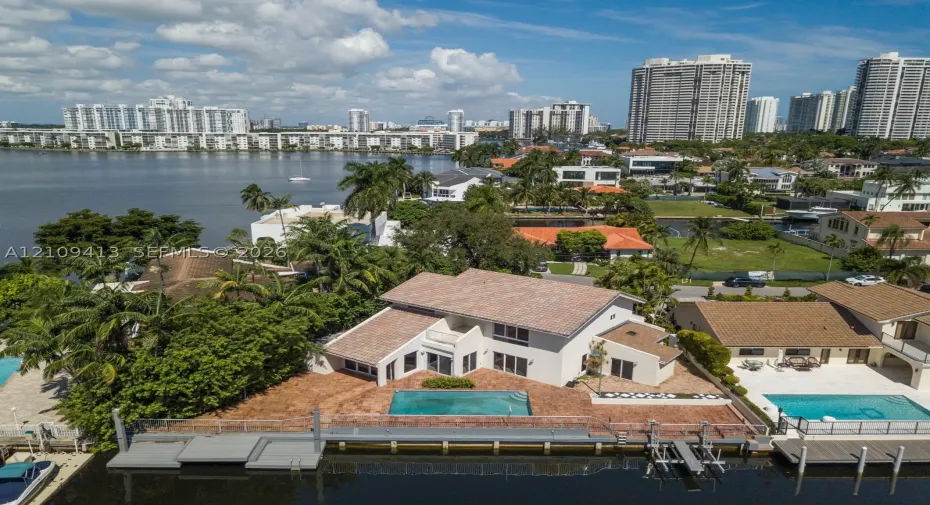 Waterfront property featuring a private boat dock, in-ground swimming pool, masonry exterior, and tile roof