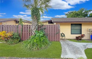 Exterior featuring stucco siding, a shingled roof, a concrete walkway, and a privacy fence