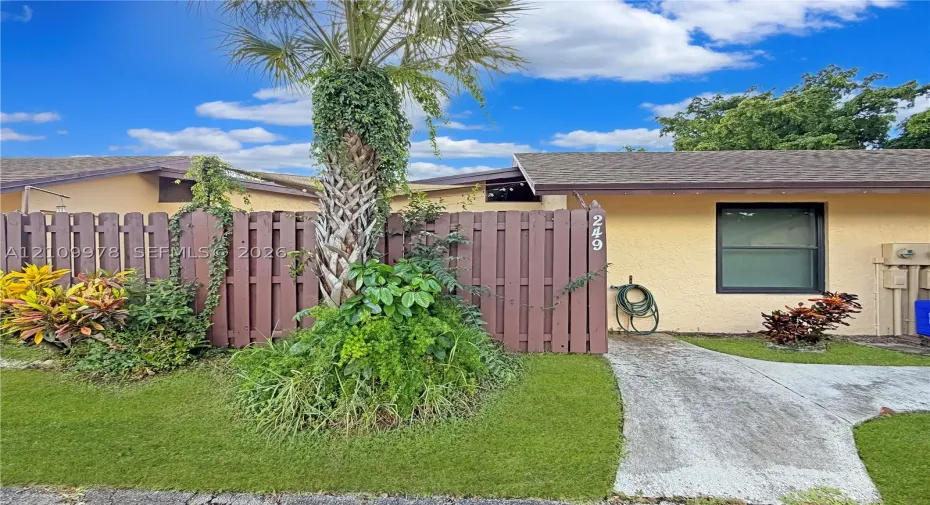 Exterior featuring stucco siding, a shingled roof, a concrete walkway, and a privacy fence