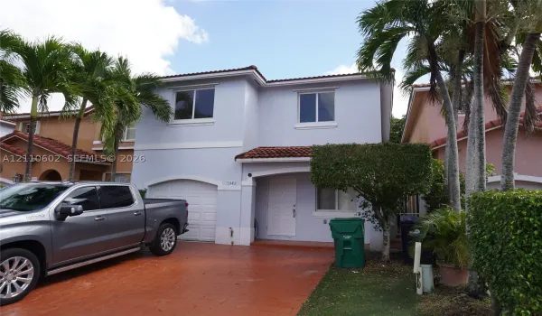 Two-story exterior featuring a stucco facade, tile roof, and a paved driveway with an integrated garage