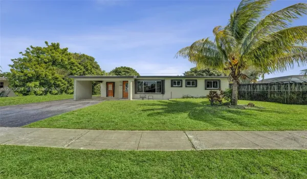 Single-story exterior featuring a stucco facade, attached carport, asphalt driveway, and mature landscaping
