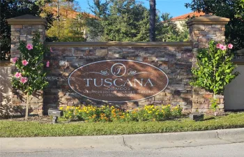 Stone-veneer community monument featuring pillars with capstones, embedded oval signage, and professionally landscaped flower beds