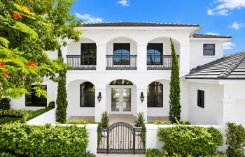 Spanish Colonial residence featuring a pristine white stucco exterior with arched openings, decorative wrought-iron balconies, and dark-framed arched windows