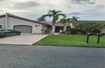 Stucco exterior featuring a concrete tile roof, an arched garage entrance, and a paved driveway