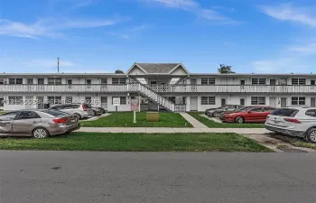 Two-story building with white exterior finish, featuring multiple entry doors and ground-level windows