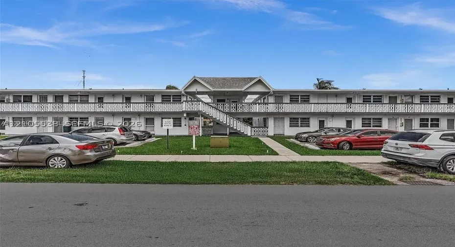 Two-story building with white exterior finish, featuring multiple entry doors and ground-level windows