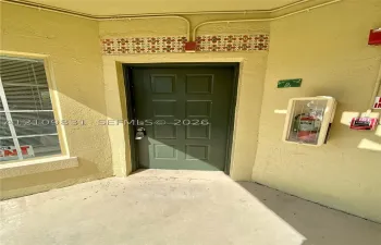 Entrance featuring a paneled olive green door, decorative tile accent trim, and textured stucco exterior finish
