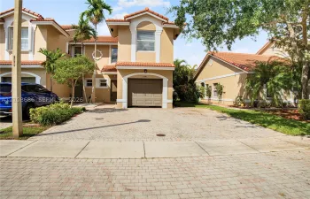 Stucco exterior with a tiled roof, attached garage, and paved driveway