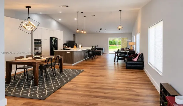 Vaulted ceilings, wood-finish flooring, kitchen island with stone countertop, recessed lighting, and geometric pendant fixtures