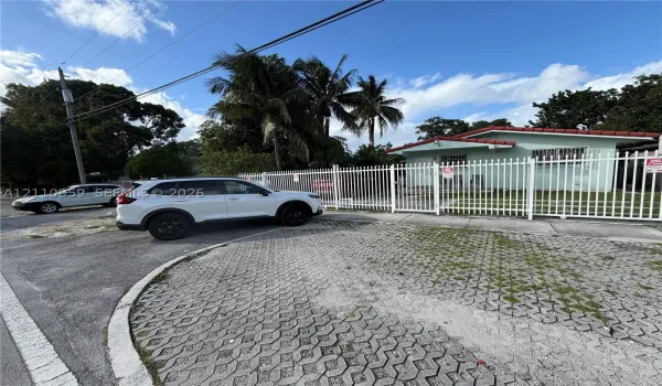 Exterior featuring a gated perimeter fence, concrete paver driveway, and mature palm​​‌​​​​‌​​‌‌​‌‌​​​‌‌​‌​‌​‌​​​‌​​ trees