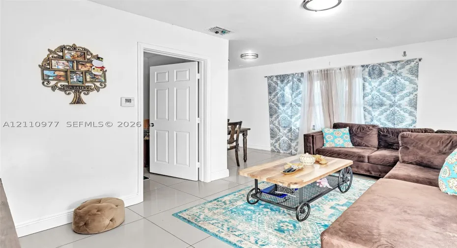 Large-format tile flooring, flush-mount ceiling lighting, and a multi-panel interior door
