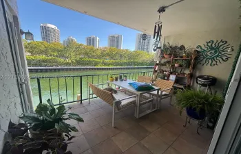 Covered balcony featuring tile flooring and a metal railing overlooking the waterway