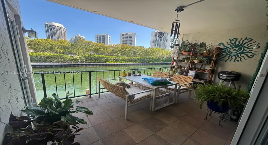 Covered balcony featuring tile flooring and a metal railing overlooking the waterway