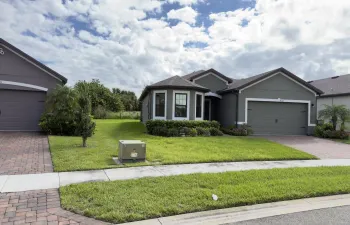 Stucco exterior residence featuring a multi-gable roofline, attached two-car garage, bay window architecture, and paved driveway