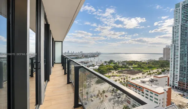 Covered balcony featuring wood-finish tile flooring, sleek black metal railings, and integrated glass panels
