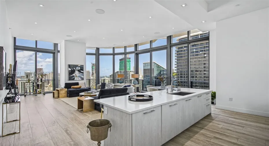 Open-concept kitchen featuring a center island with light-toned cabinetry and a stone-look countertop, floor-to-ceiling windows, wood-finish flooring, and recessed ceiling lighting