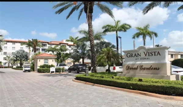 Gran Vista at Doral community entrance featuring a masonry signage monument, paver stone driveways, mature palm trees, and manicured landscaping
