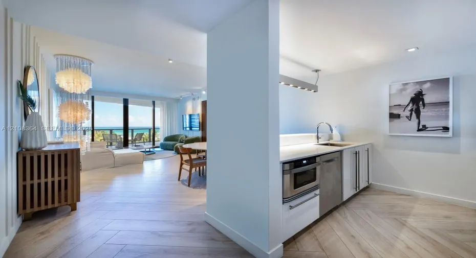 Herringbone wood-finish flooring, white flat-panel cabinetry, integrated stainless steel microwave, quartz countertops, and floor-to-ceiling glass sliding doors