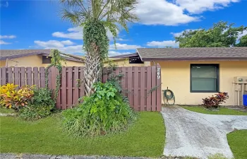 Exterior featuring stucco siding, a shingled roof, a concrete walkway, and a privacy fence