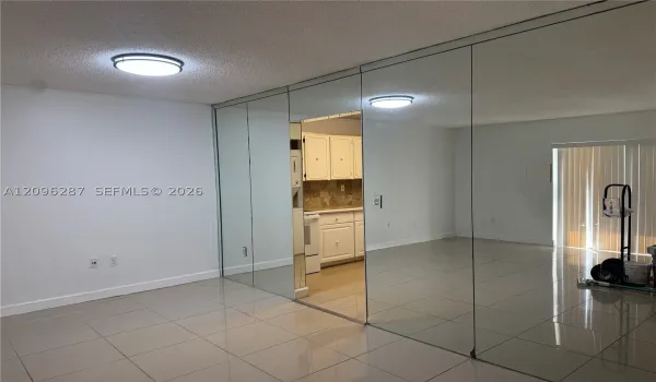 Full-wall mirrored accent, polished tile flooring, and flush-mount ceiling lighting