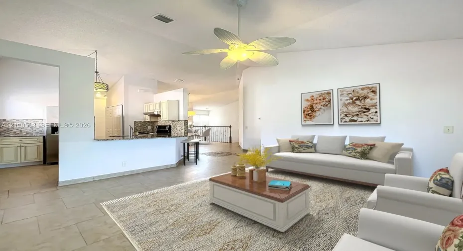 Vaulted ceilings, large-format tile flooring, kitchen featuring stone-surfaced breakfast bar, and decorative ceiling fan