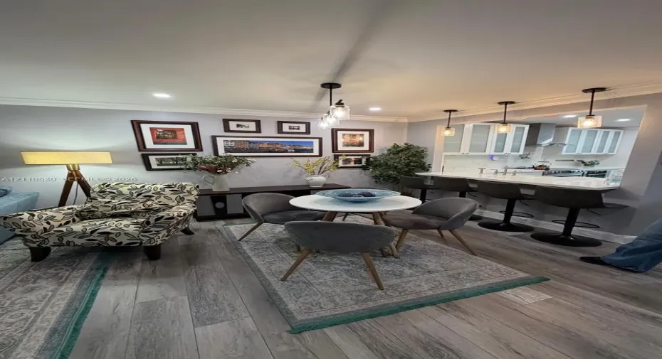 Open-concept kitchen area featuring a stone-topped breakfast bar, recessed ceiling lighting, glass-paneled cabinetry, wood-finish flooring, and crown molding