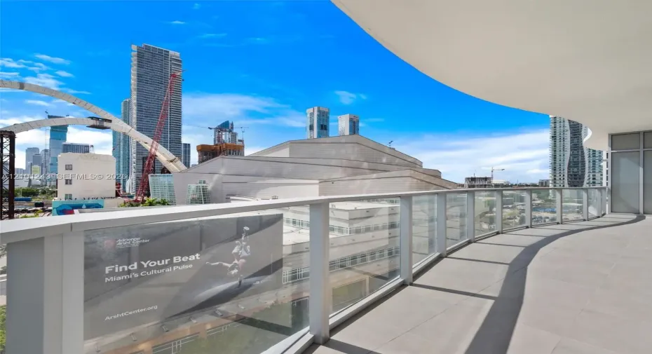 Curved balcony featuring tile flooring and a glass-paneled railing