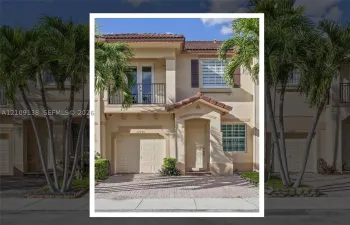 Two-story exterior featuring a paved driveway, integrated garage, upper-level balcony with metal railing, and tile roof
