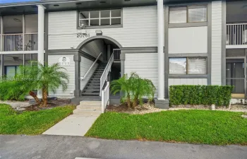 Multi-story exterior featuring lap siding, arched entryway, staircase with metal railing, private balconies, and landscaped grounds