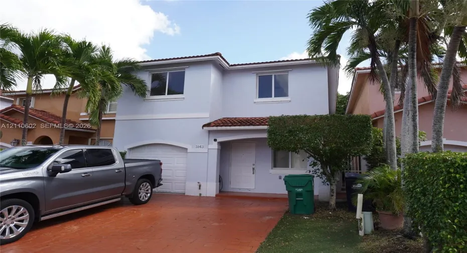 Two-story exterior featuring a stucco facade, tile roof, and a paved driveway with an integrated garage