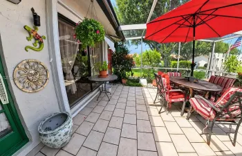 Screened lanai featuring tiled flooring, sliding glass door entry, and outdoor access to the grounds