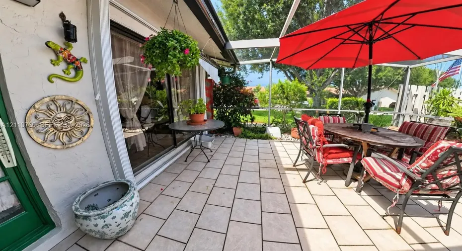 Screened lanai featuring tiled flooring, sliding glass door entry, and outdoor access to the grounds