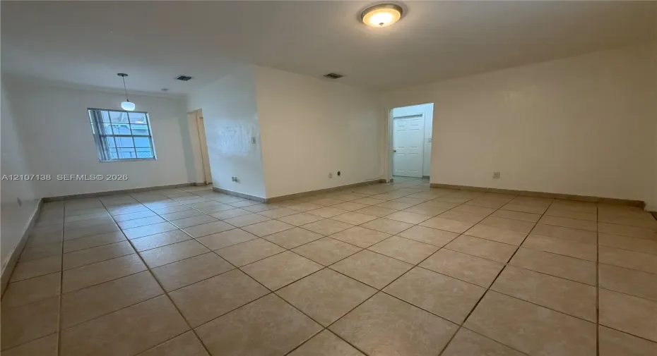 Interior space featuring neutral wall paint, large-format tile flooring, a hanging pendant light, and a flush-mount ceiling fixture