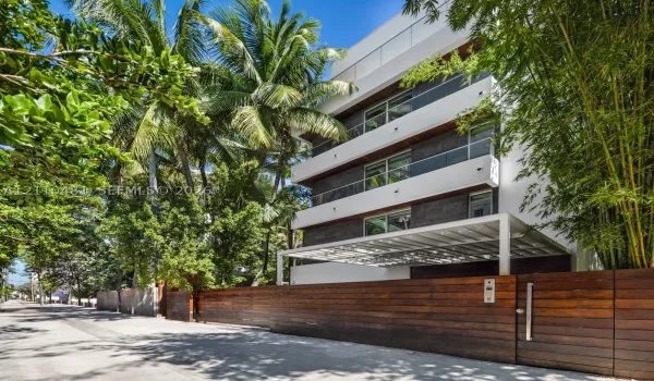 Multi-story contemporary exterior featuring horizontal wood siding, smooth white stucco facade, glass balcony railings, and a gated entrance with horizontal wood fencing