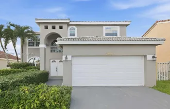 Two-story exterior featuring a stucco facade, arched entryway, double-door entrance, arched windows, and a tiled roof