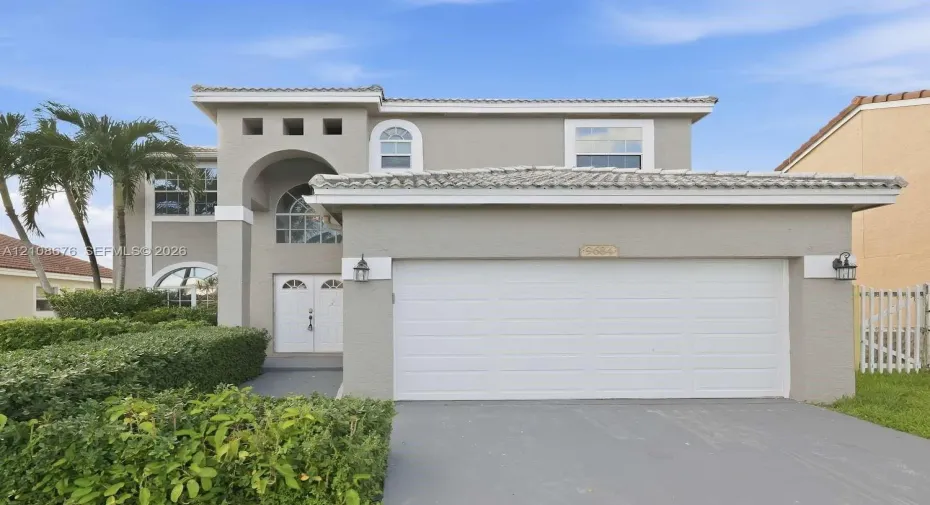 Two-story exterior featuring a stucco facade, arched entryway, double-door entrance, arched windows, and a tiled roof
