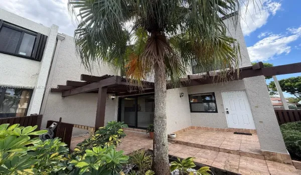 Stucco exterior featuring a timber pergola, tiled patio, sliding glass door, and integrated outdoor lighting