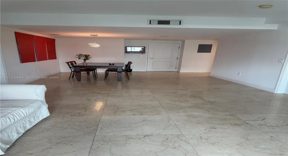 Large-format polished stone flooring with neutral veining and a single pendant light fixture