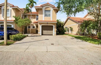 Stucco exterior with a tiled roof, attached garage, and paved driveway