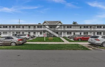 Two-story building with white exterior finish, featuring multiple entry doors and ground-level windows