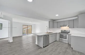 Kitchen featuring grey shaker-style cabinetry, stone-pattern countertops, stainless steel appliances, and wood-finish flooring