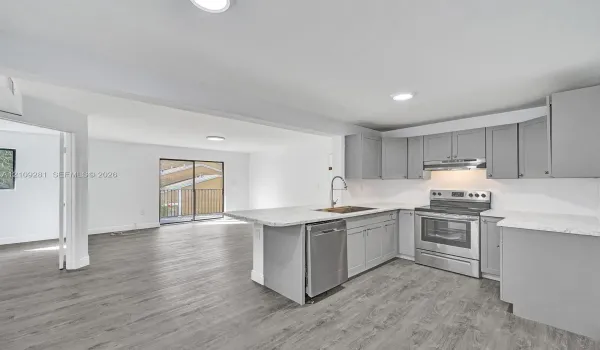 Kitchen featuring grey shaker-style cabinetry, stone-pattern countertops, stainless steel appliances, and wood-finish flooring