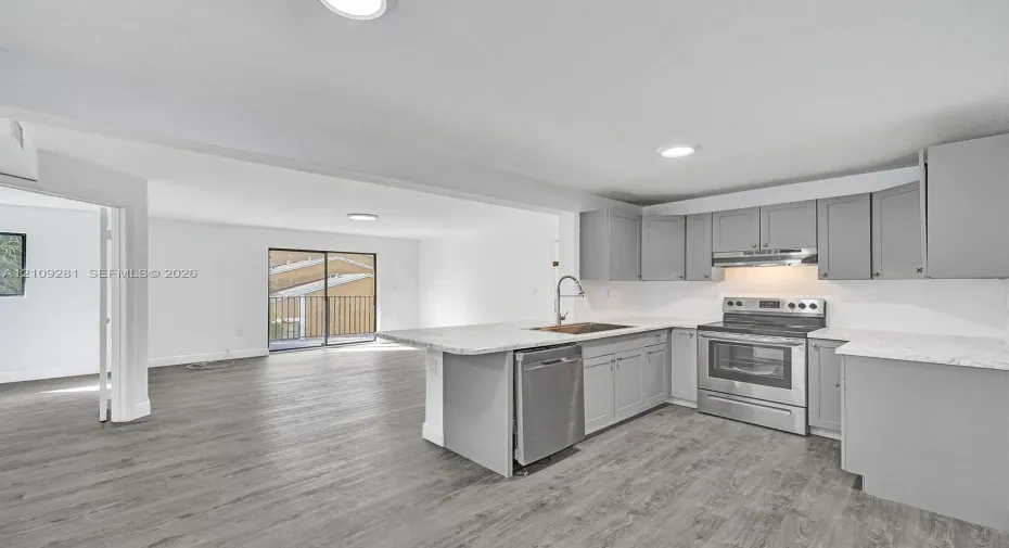 Kitchen featuring grey shaker-style cabinetry, stone-pattern countertops, stainless steel appliances, and wood-finish flooring