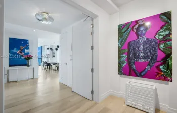 Interior hallway featuring wood-finish flooring, smooth-finish walls, ceiling-mounted circular lighting, and a full-height interior door with metal hinges