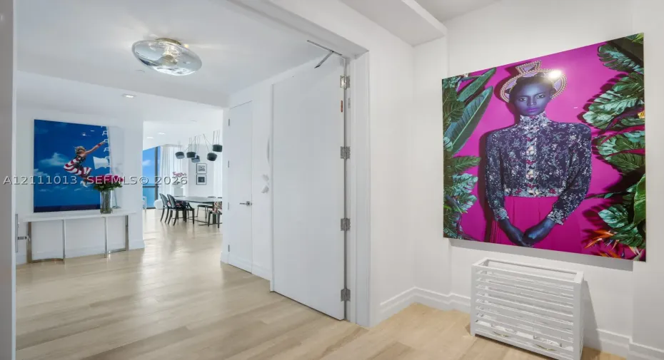Interior hallway featuring wood-finish flooring, smooth-finish walls, ceiling-mounted circular lighting, and a full-height interior door with metal hinges