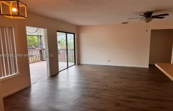Living area featuring wood-finish flooring, sliding glass doors to a covered deck, pendant lighting, and a ceiling fan
