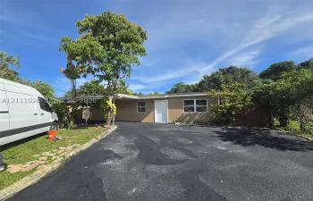 Single-story exterior featuring a paved driveway, attached carport, and dual-pane windows