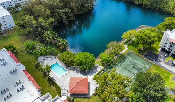 Waterfront property grounds featuring a swimming pool, a covered gazebo, a fenced tennis court, and mature landscaping